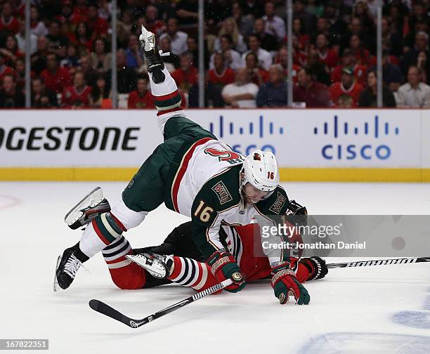 Jason Zucker of the Minnesota Wild falls over Johnny Oduya of the Chicago Blackhawks in Game One of the Western Conference Quarterfinals during the...