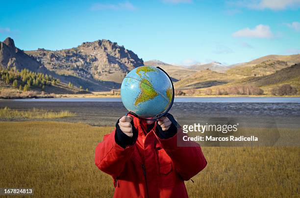 boy holding globe in patagonian steppe - south america stock-fotos und bilder