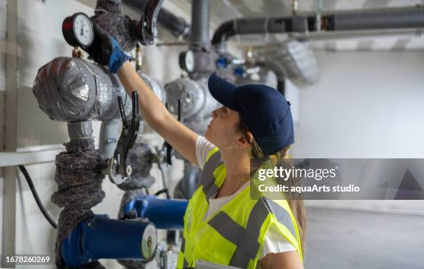 female engineer checking boiler system in a basement - boiler engineer stockfoto's en -beelden