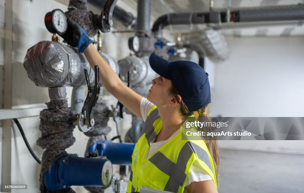 Female Engineer Checking Boiler System In A Basement