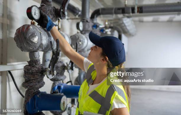 female engineer checking boiler system in a basement - bomba de água equipamento imagens e fotografias de stock