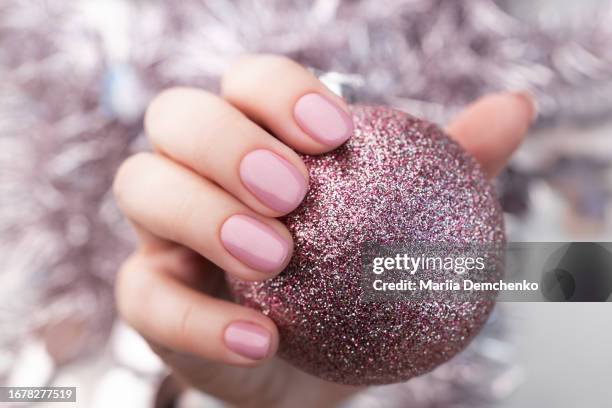 hand with pink glitter christmas ball and pink gel fingernails - nail art stock pictures, royalty-free photos & images