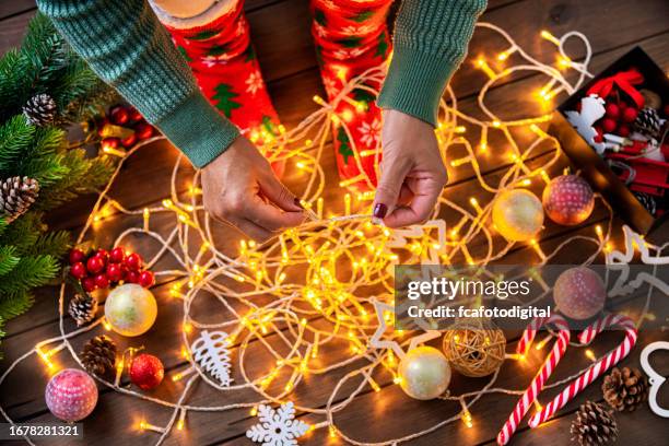 woman untangling christmas string lights - christmas lights stock pictures, royalty-free photos & images