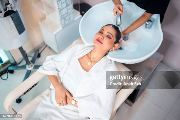 young woman enjoying while getting her hair washed by professional hairdresser - beauty salon stock pictures, royalty-free photos & images