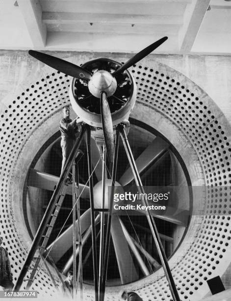 An aviation engineer stands on a ladder to reach an aerial engine on the balance at the entrance of the new wind tunnel ready for testing at the...