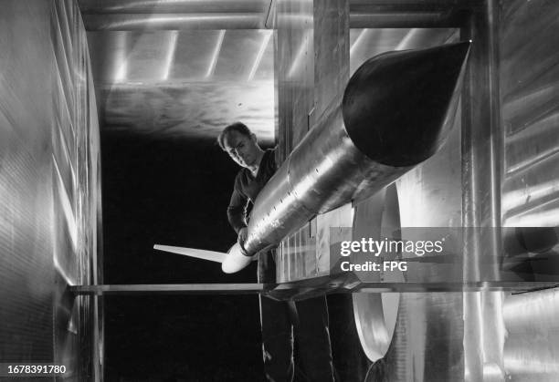 An aviation engineer with a model aircraft fixed in the supersonic wind tunnel at the Ames Aeronautical Laboratory at Moffett Federal Airfield,...