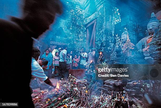 The Buddhist faithful worship in front of a statue of the Buddha inside the ruins of the Hindu Khmer temple of Wat Phu in Champasak province in...