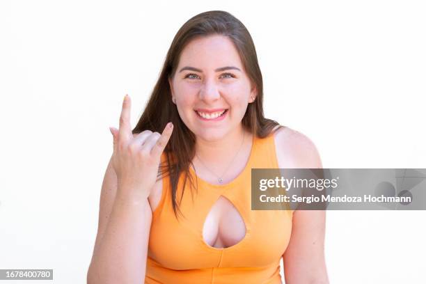 latino woman looking at the camera and doing the heavy metal horns hand sign - metal music stockfoto's en -beelden