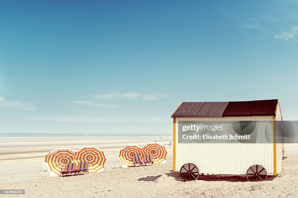 Beach hut and several sun shades along beach