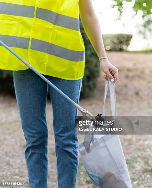 unrecognizable woman picking up waste in a public park - people picking up trash stock pictures, royalty-free photos & images
