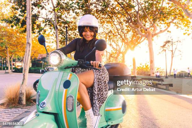 latin woman using mobility service with a classic electric moped in the barcelona city. - montare-su-un-veicolo foto e immagini stock