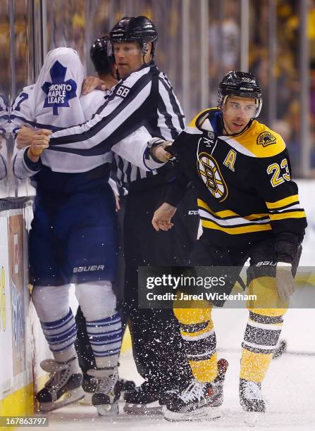 Leo Komarov of the Toronto Maple Leafs attempts to continue fighting Chris Kelly of the Boston Bruins by grabbing his arm after having his jersey...