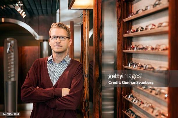 man standing in shop surrounded by glasses. - optician stockfoto's en -beelden