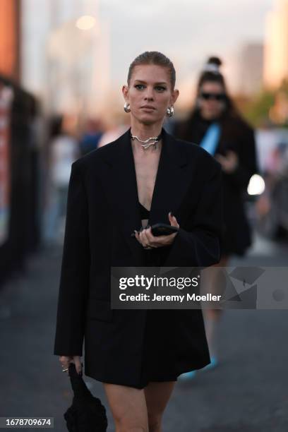 Fashion Week guest is seen wearing silver chunky hoop earrings, a silver choker, a black oversized blazer, several silver rings and a black quilted...