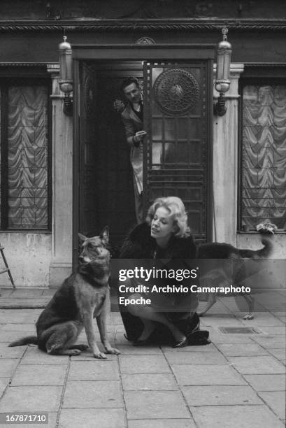 Anna Maria Proclemer plays with her German Shepherd in front of the Fenice Theater in 1961 in Venice, Italy.