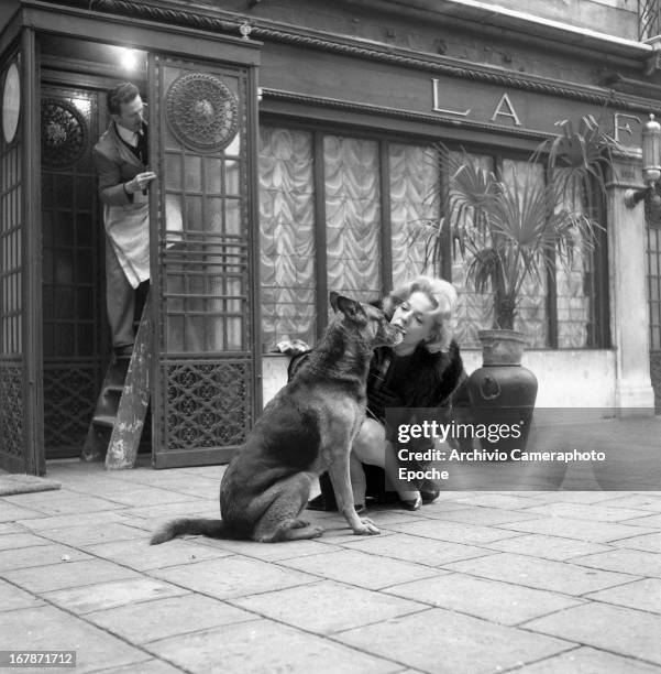 Anna Maria Proclemer plays with her German Shepherd in front of La Fenice Theater in 1961 in Venice, Italy.