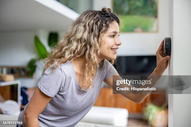 donna a casa usando un termostato intelligente - termostato foto e immagini stock