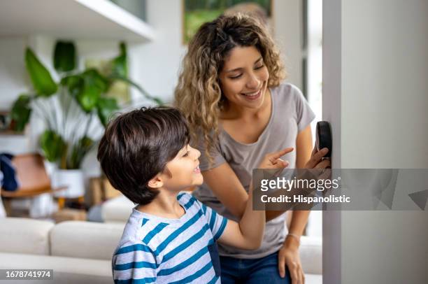 mother and son at home using a smart thermostat - bijstellen stockfoto's en -beelden