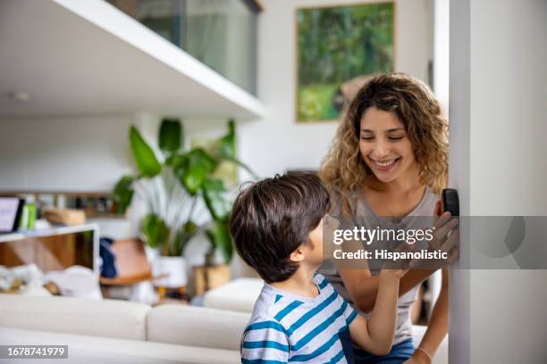 madre e figlio a casa regolano la temperatura usando un termostato intelligente - termostato foto e immagini stock