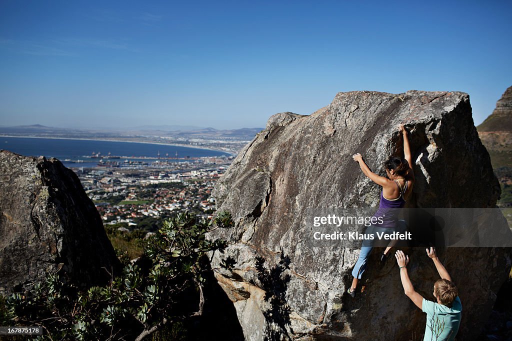 Woman climbing on rock, man assisting