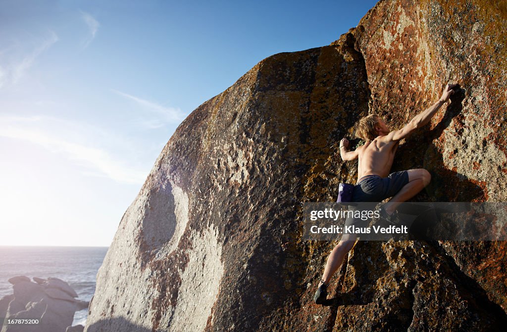 Man climbing on rock side, backlight