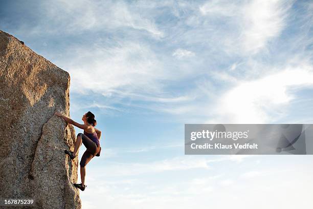 woman climbing rock side - alpinismo fotografías e imágenes de stock