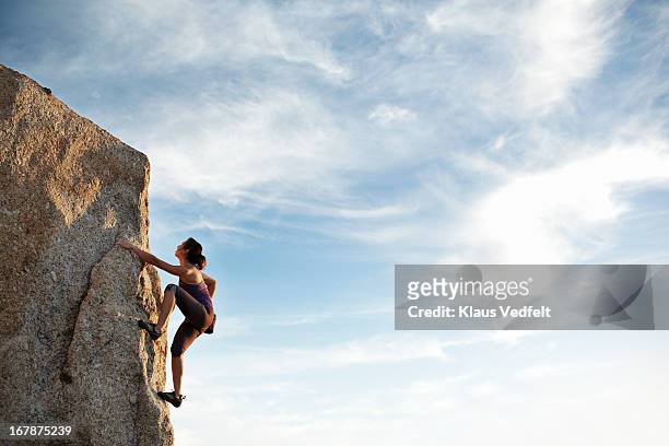 woman climbing rock side - courage photos et images de collection