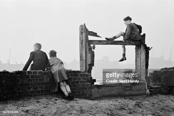 Three boys watching the shipping in the Pool of London from the north bank of the Thames at Wapping, east London, December 1949. Original...