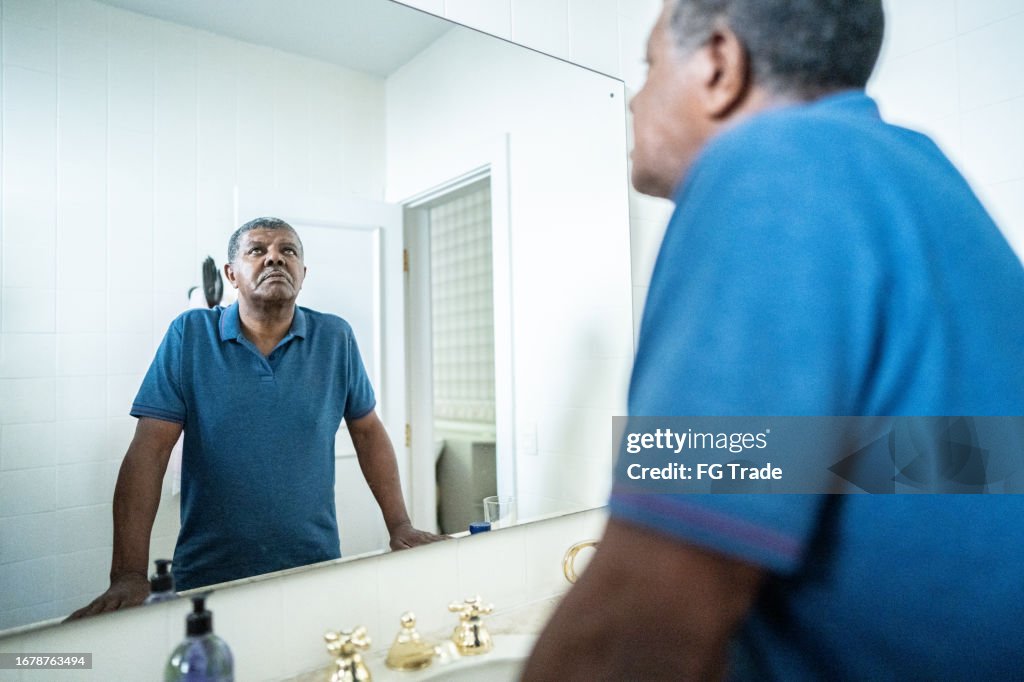 Sad senior man in the bathroom at home