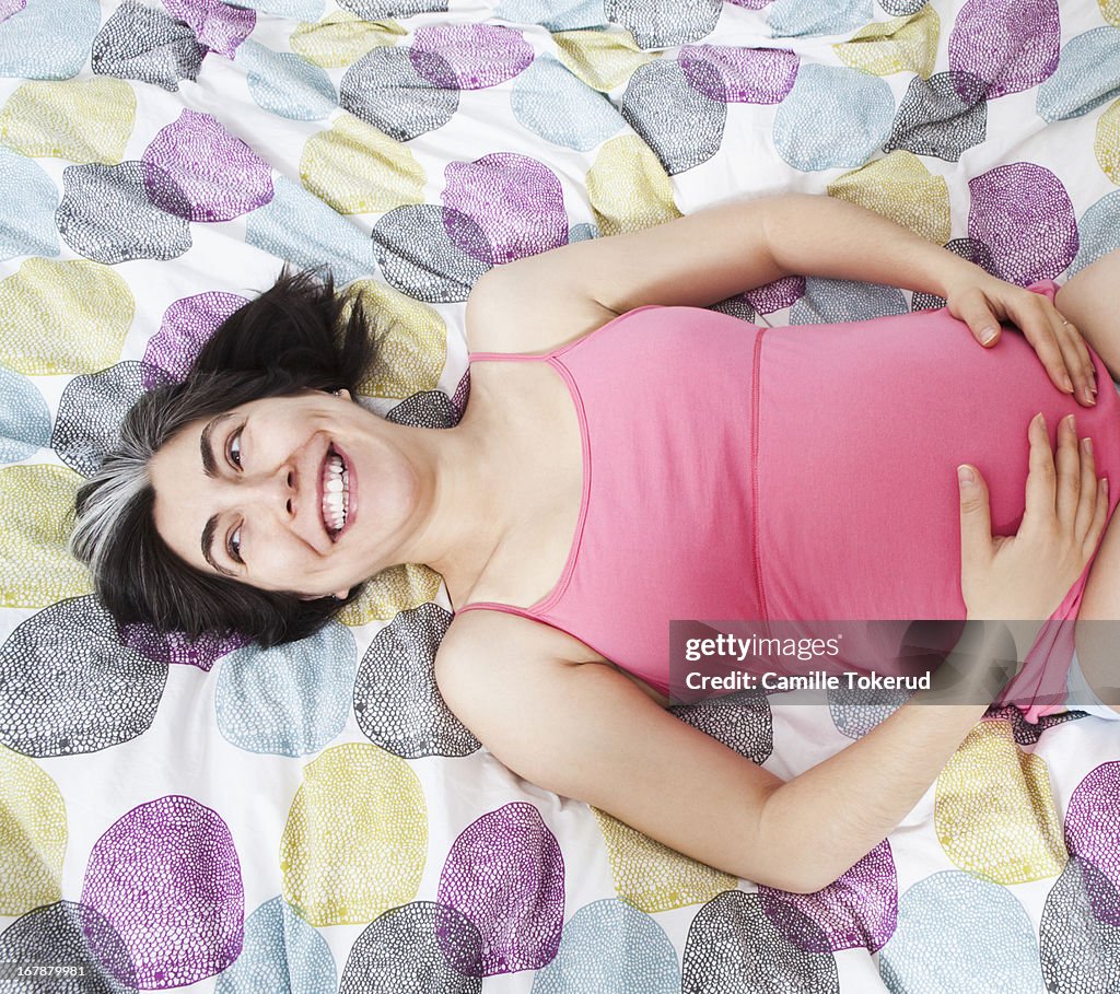 Pregnant woman on bed smiling