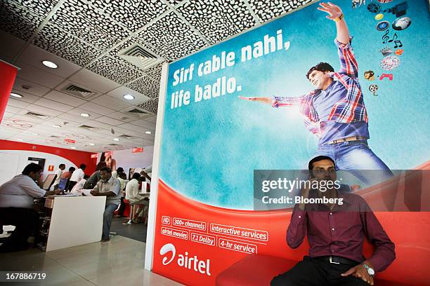 Man talks on his mobile phone in front of a Bharti Airtel Ltd. Advertisement at the company's flagship store in Mumbai, India on Thursday, May 2,...