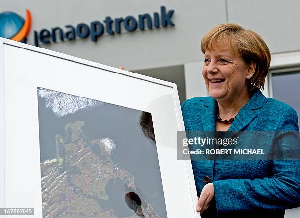 German Chancellor Angela Merkel holds a picture of Baltic Sea Island of Ruegen after a visit of the Jena-Optronik GmbH , a German provider of...