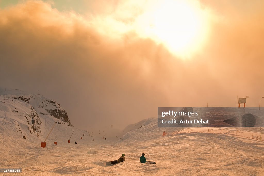 Ski resort in the Alps at sunset with skiers.