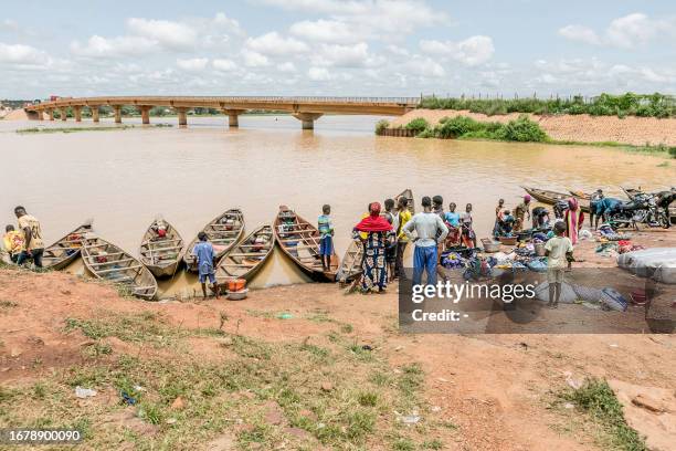 Passengers gather near informal motorised canoes ready to ferry passengers across the River Niger that divides Benin and Niger in the town of...