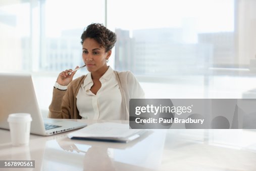 Mujer de negocios utilizando el ordenador portátil en oficina Mujer de negocios utilizando el ordenador portátil en oficina