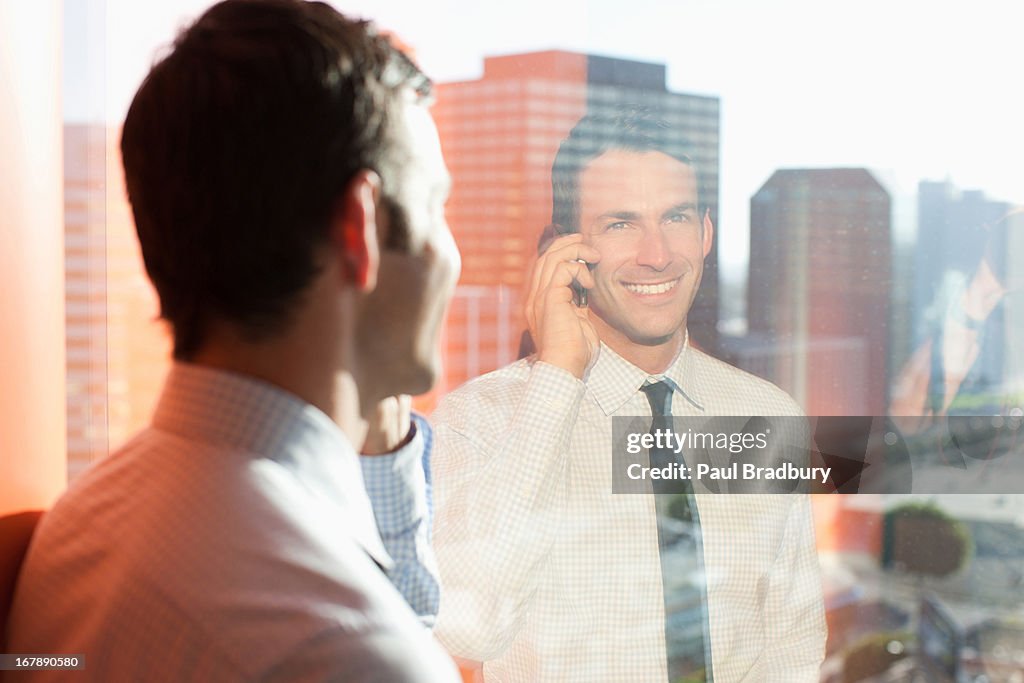 Businessman talking on cell phone at window