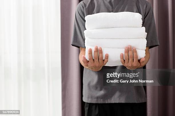 male housekeeper in hotel holding towels - towel stock pictures, royalty-free photos & images