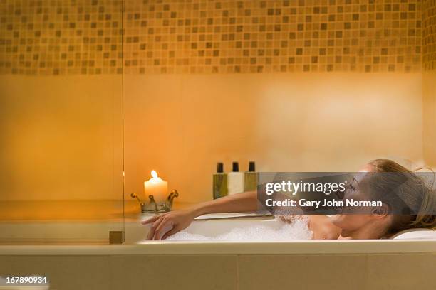 young woman relaxing in bubbly bath - woman bath bubbles stock-fotos und bilder