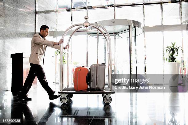 bellboy pushing luggage trolley - bellhop foto e immagini stock