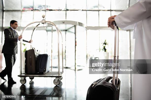 bellboy pushing luggage trolley - luggage trolley stock pictures, royalty-free photos & images