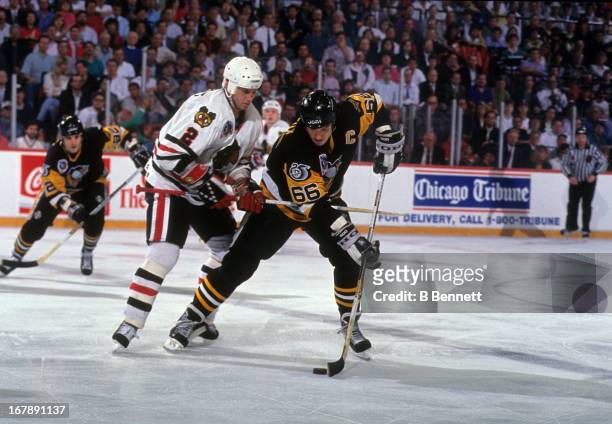 Mario Lemieux of the Pittsburgh Penguins skates with the puck as he is defended by Bryan Marchment of the Chicago Blackhawks during Game 4 of the...