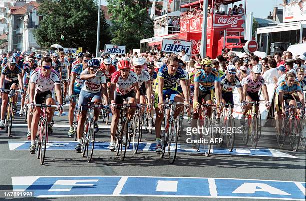 Riders of the Tour de France cross the finish line together at the end of the 16th stage between Tarbes and Pau on July 19 in memory of Italian rider...
