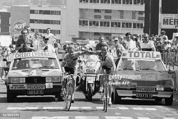 Frenchman Bernard Hinault and his teammate US Greg Lemond smile as they cross the finish line together at the end of the 18th stage of the Tour de...