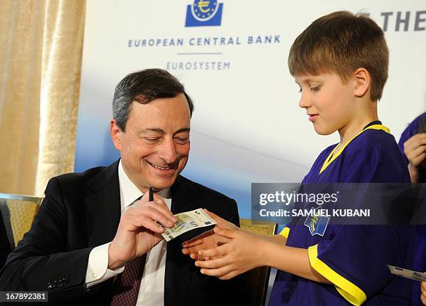 European Central Bank President Mario Draghi signs a new five-euro banknote during a press conference following the Governing Council Meeting of...