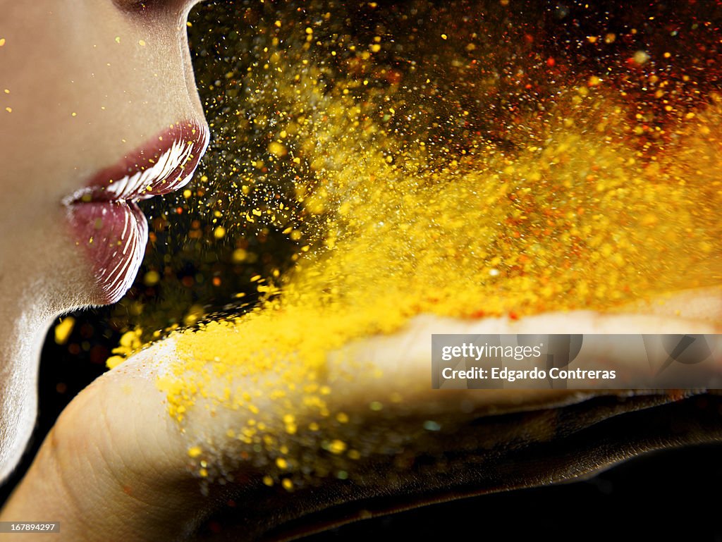 Close up of a mouth blowing on yellow dust