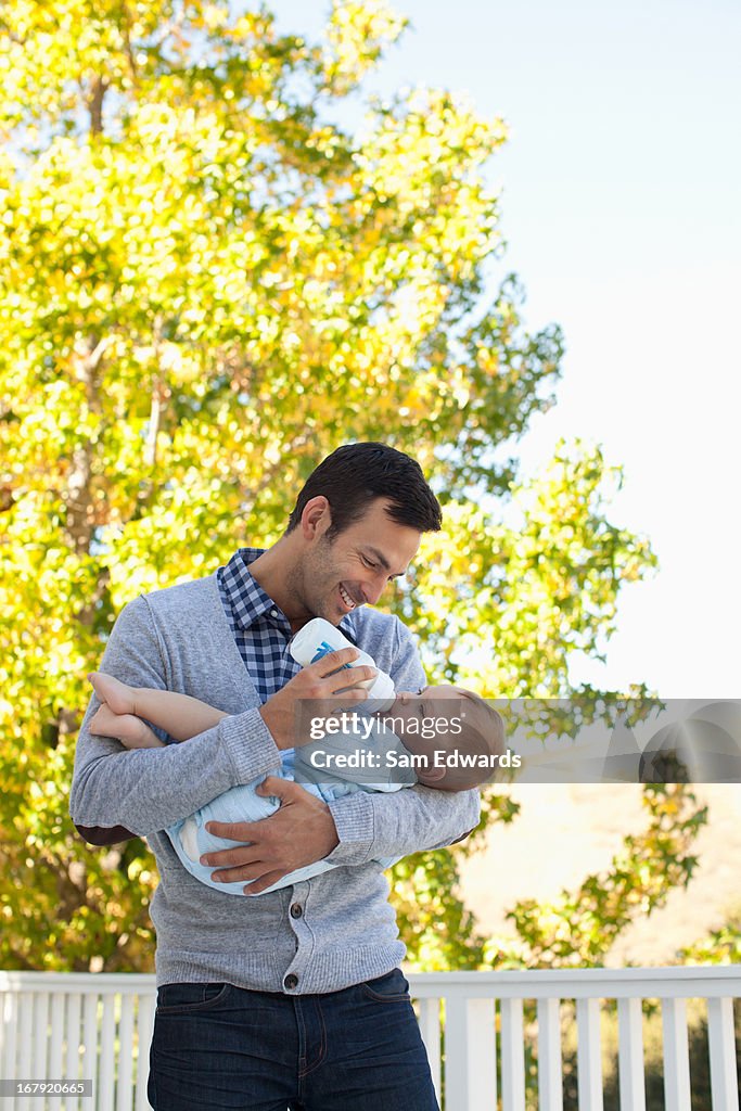 Father bottle feeding son outdoors