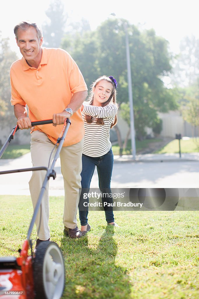 Father and daughter mowing lawn together