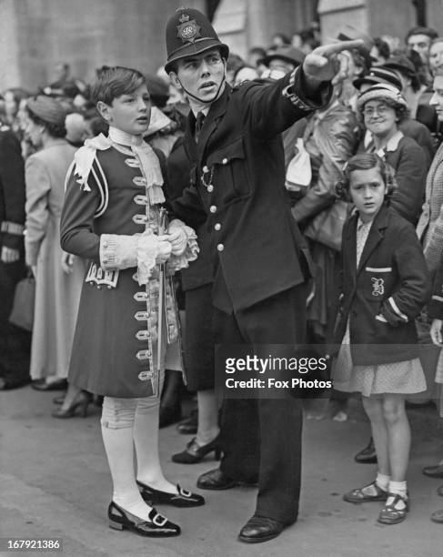 The Hon. William Grosvenor, page to Lord Churston, gets directions from a policeman outside Westminster Abbey after a full dress rehearsal for the...