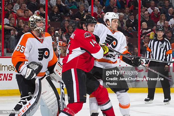 Steve Mason and Oliver Lauridsen of the Philadelphia Flyers guard against Colin Greening of the Ottawa Senators during an NHL game, at Scotiabank...