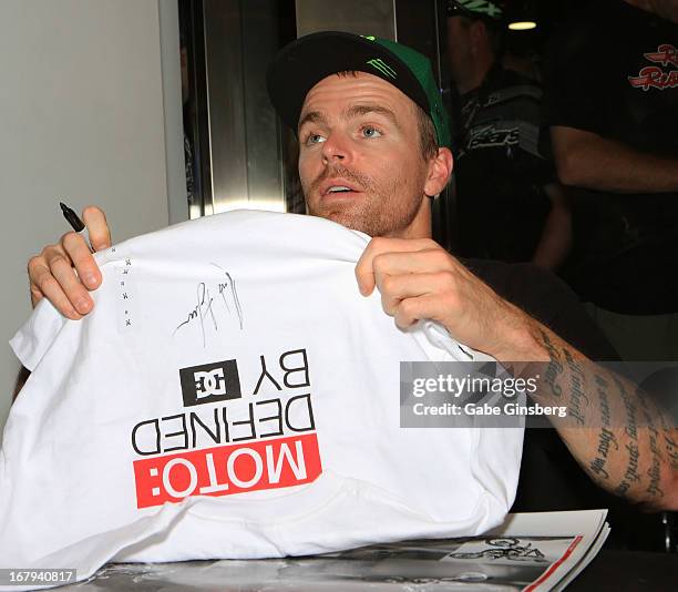 Motorcross rider Nate Adams hands fan back an autographed t-shirt during a DC Moto Team appearance in celebration of the 2013 AMA Supercross Finals...